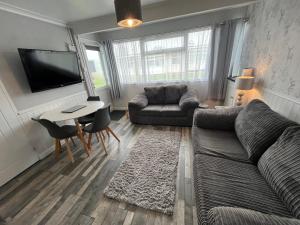 een woonkamer met een bank en een tafel bij 170 Chalet, Sunbeach, Scratby - Two bed chalet, sleeps 5, pet friendly, free Wi-Fi plus free entry to onsite clubhouse in Scratby