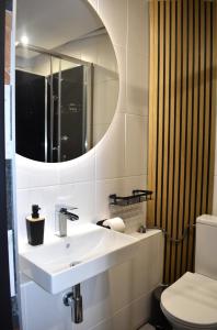 a white bathroom with a sink and a mirror at Apartament MCK 100m, Spodek 150m, NOSPR in Katowice