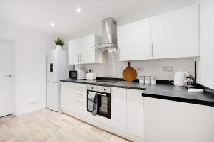a kitchen with white cabinets and black counter tops at Newly refurbished Near the coast Sleeps 5 in Newbiggin-by-the-Sea