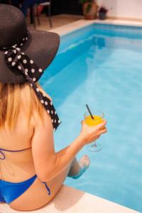 a woman in a bikini holding a drink next to a pool at Apartments Gabrieri in Dubrovnik