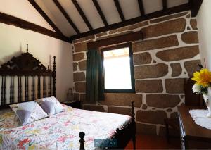 a bedroom with a bed and a stone wall at MyStay - Casa do Vale JC in Vila Nune