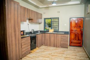 a kitchen with wooden cabinets and a black stove at Kamps Apartment - Foxdale Forest in Lusaka