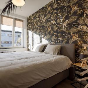 una camera da letto con un grande letto e carta da parati tropicale di Gîtes in Huy - Appartements chaleureux dans le centre de Huy a Huy