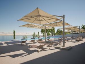 a group of chairs and umbrellas next to a pool at Mobile homes at Aminess Avalona Resort, Island Pag in Povljana
