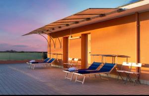 un groupe de chaises et de tables sur le toit d'un bâtiment dans l'établissement Hotel Kursaal, à Bellaria-Igea Marina