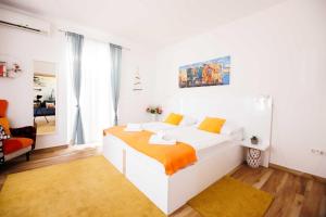 a white bedroom with a bed with an orange blanket at Apartments Gabrieri in Dubrovnik