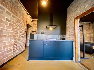 uma cozinha com armários azuis e uma parede de tijolos em Zielona Park Industrial Studio em Dabrowa Górnicza