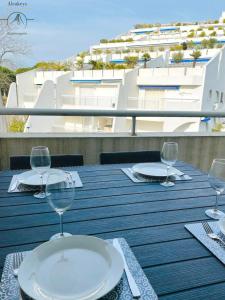 un tavolo con bicchieri da vino su un balcone con un edificio di L'OSLO Superbe T2 - à 3 min de la mer - clim / wifi - 1 Chambre a La Grande-Motte