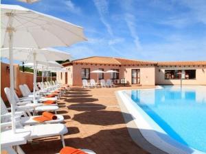 a pool with chairs and umbrellas next to a building at Apartment in Vignola Mare near Sandy Beach in Vignola Mare