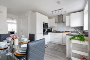 a kitchen with white cabinets and a table with chairs at NEW Luton 3 Bedroom house, Contractors & families, Sleeps 7 with Free Parking & WIFI in Luton
