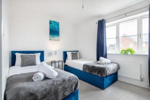 a bedroom with two beds and a window at NEW Luton 3 Bedroom house, Contractors & families, Sleeps 7 with Free Parking & WIFI in Luton