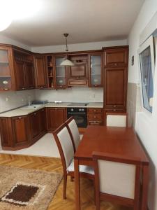 a kitchen with wooden cabinets and a table and chairs at Jana apartments 2 in Tivat