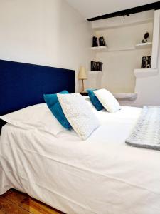 a white bed with blue and white pillows on it at Le Chardon Bleu, jardin, centre-ville, Saint-Côme-d'Olt in Saint-Côme-dʼOlt