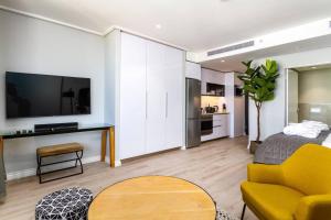 een woonkamer met een gele bank en een tafel bij Cape Town Bree Street 27th Floor Studio Apt Views in Kaapstad