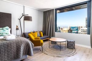 een slaapkamer met een bed, een stoel en een raam bij Cape Town Bree Street 27th Floor Studio Apt Views in Kaapstad