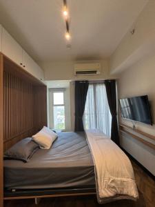 a bedroom with a bed with a window and a flat screen tv at Studio Amor Apartemen Pakuwon City Mall in Surabaya