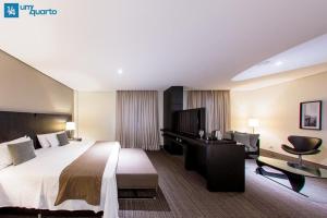 クリチバにあるMANHATTAN FLOORの大きなベッドとデスクが備わるホテルルームです。