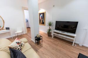 ein Wohnzimmer mit einem Sofa und einem Flachbild-TV in der Unterkunft L’orecchino di perla [Politeama Rossetti] in Triest