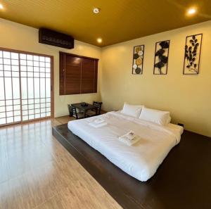 a bedroom with a large white bed in a room at COZY SHIROI RESORT in Nang Rong