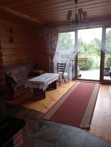 een woonkamer met een tafel en een groot raam bij Drewniana chatka in Budy Stare