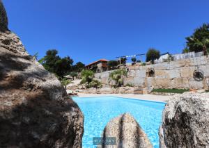 a swimming pool with rocks in front of a house at MyStay - Casa do Vale JC in Vila Nune