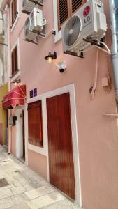 um edifício cor-de-rosa com uma ventoinha e uma porta em Rogdogg apartments center Zadar em Zadar