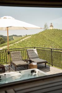 eine Terrasse mit Stühlen, einem Sonnenschirm und einer Badewanne in der Unterkunft Winzer Appartements Kogler in Leutschach