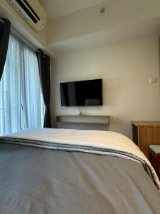 a bedroom with a bed and a flat screen tv at Studio Amor Apartemen Pakuwon City Mall in Surabaya