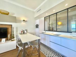 a kitchen with white cabinets and a table and chairs at Gallia Park by Welcome to Cannes in Cannes