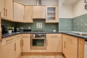 uma cozinha com armários de madeira e um forno com placa de fogão em Comfy Home on Burton Road em Derby