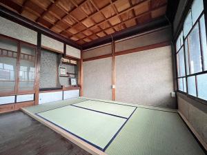 ein leeres Zimmer mit einem Tisch in einem Zimmer mit Fenstern in der Unterkunft Hostel Miyagawa by Murasaki Ryokan in Takayama