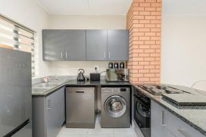 a kitchen with a washing machine and a sink at Waterfall Ridge - Retreat in the heart of Midrand in Midrand
