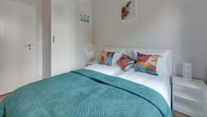 um quarto branco com uma cama com lençóis e almofadas azuis em Lion Apartments - SCALA City Center Apartments&Studio IC em Gdansk