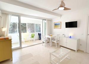 ein weißes Wohnzimmer mit einem Tisch und Stühlen in der Unterkunft 1 Bedroom Apartment Second Line Beach- Parque Marbella Building in Marbella
