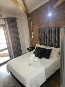 a bedroom with a large white bed with a brick wall at Dream Abodes at Cozy Craftmans Ship, Maboneng in Johannesburg