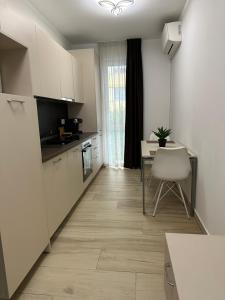 a kitchen with white cabinets and a table with a chair at Covaciu aparthotel in Cluj-Napoca