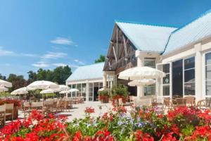 un patio con sombrillas, mesas, sillas y flores en Mobilhome 5 étoiles - Parc aquatique - eebfec, en Sainte-Catherine-de-Fierbois