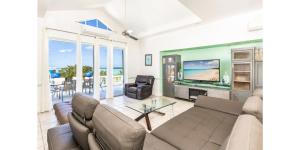 ein Wohnzimmer mit einem Sofa und einem TV in der Unterkunft NEW Waterside Home Whirlpool Spa Tub Smart TV in Providenciales