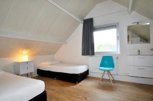 a room with two beds and a blue chair at Vakantiepark Bosmeer Friesland in Noordwolde