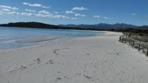 una playa de arena con valla y agua en Le pergole en Olbia