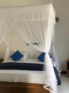 a bedroom with a bed with a canopy and blue pillows at La Casa Mirissa in Mirissa