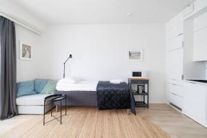 a white bedroom with a bed and a chair at ULEABO New & Cozy Top Floor Studio in Oulu