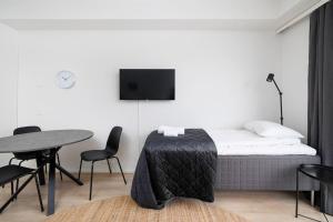 a bedroom with a bed and a table and a tv at ULEABO New & Cozy Top Floor Studio in Oulu