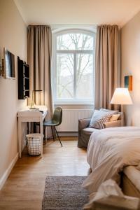 a bedroom with a bed and a desk and a window at Aarskogs Boutique Hotel in Glücksburg
