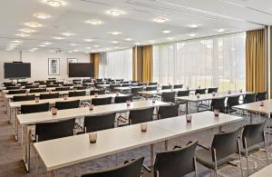 an empty lecture room with tables and chairs at Leonardo Hotel Esslingen in Esslingen