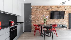 グダニスクにあるLion Apartments - SCALA City Center Apartments&Parking IBのレンガの壁、テーブルと椅子付きのキッチンが備わります。