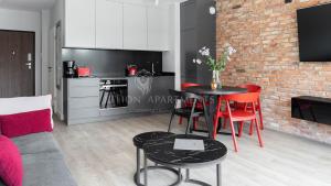 a kitchen and a living room with a table and chairs at Lion Apartments - SCALA City Center Apartments&Parking IB in Gdańsk