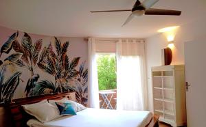 1 dormitorio con 1 cama con papel pintado tropical en Le vol du Cardinal, en Saint-Pierre