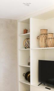 a white book shelf with a tv in a room at Nomad Houses - Casa Sarilho in Beja