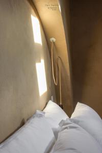 a bed with white sheets and a light on the wall at Nomad Houses - Casa Sarilho in Beja +20 photos